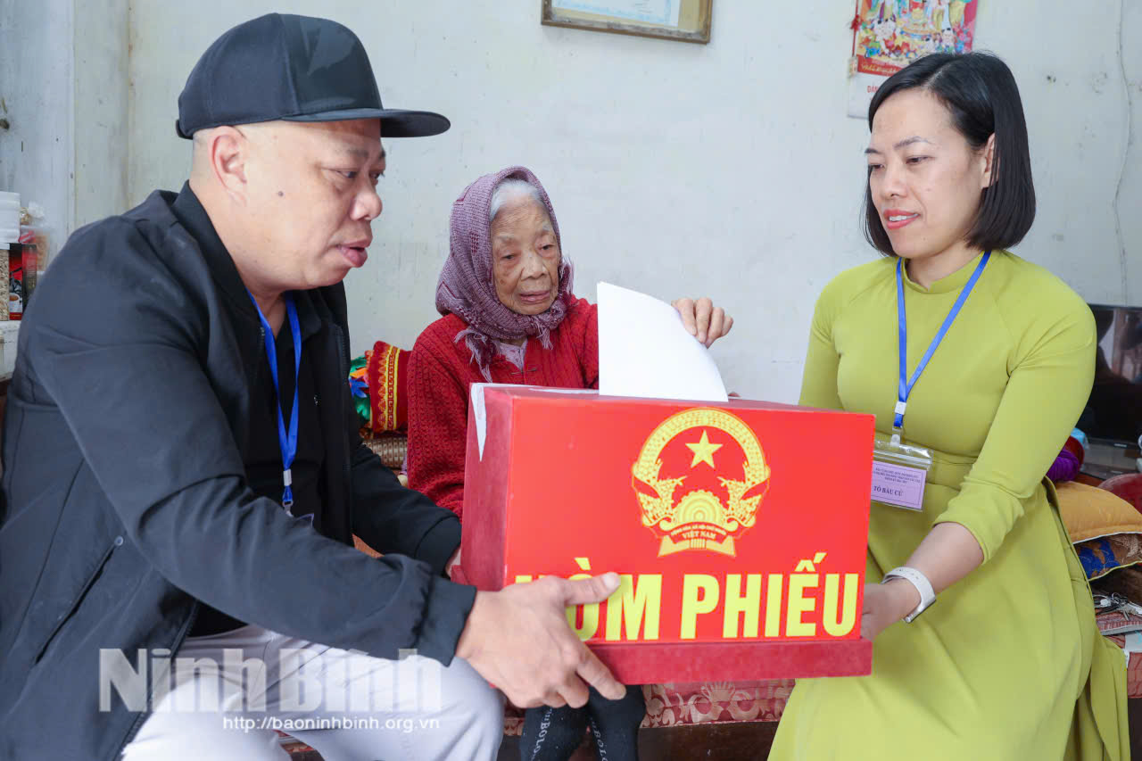 Cán bộ Tổ bầu cử số 42 (tổ dân phố Liễu Văn, phường Nam Định) đưa hòm phiếu phụ đến tận nhà cử tri Trần Thị Gái (97 tuổi) để thực hiện quyền bầu cử. Ảnh: Viết Dư