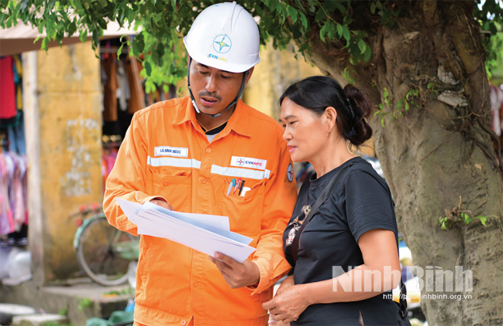 Nhân viên Công ty Điện lực Ninh Bình hướng dẫn người dân xã Vạn Thắng thanh toán tiền điện không dùng tiền mặt. Ảnh: Trường Giang