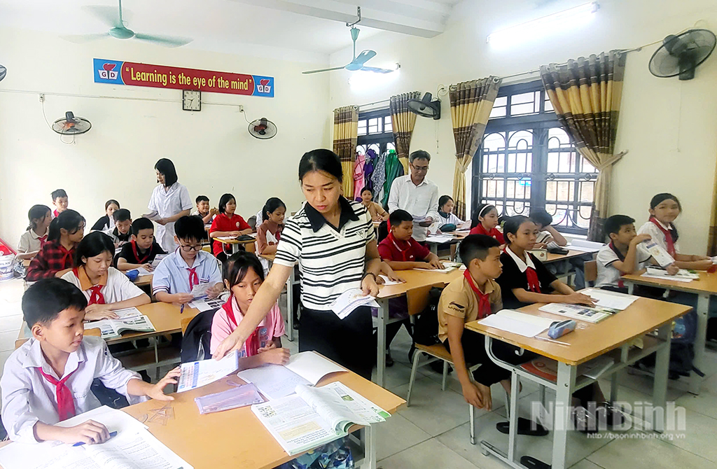 Cán bộ BHXH cơ sở Gia Viễn phối hợp với Trường Tiểu học và THCS Gia Vượng (xã Gia Viễn) tuyên truyền chính sách BHYT cho học sinh.