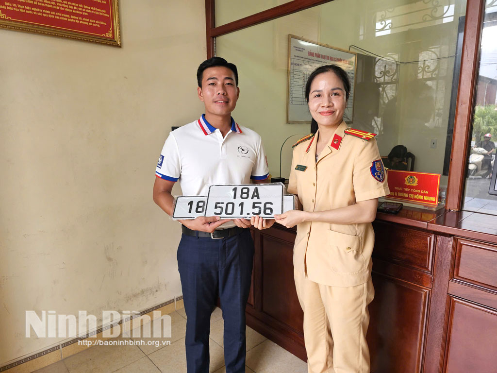 Cán bộ Phòng Cảnh sát giao thông (Công an tỉnh) trao biển số xe cho người dân tại điểm đăng ký phường Mỹ Lộc.