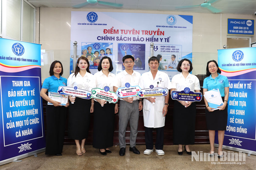 Các đại biểu chụp ảnh với các khẩu hiệu tuyên truyền về chính sách bảo hiểm y tế.