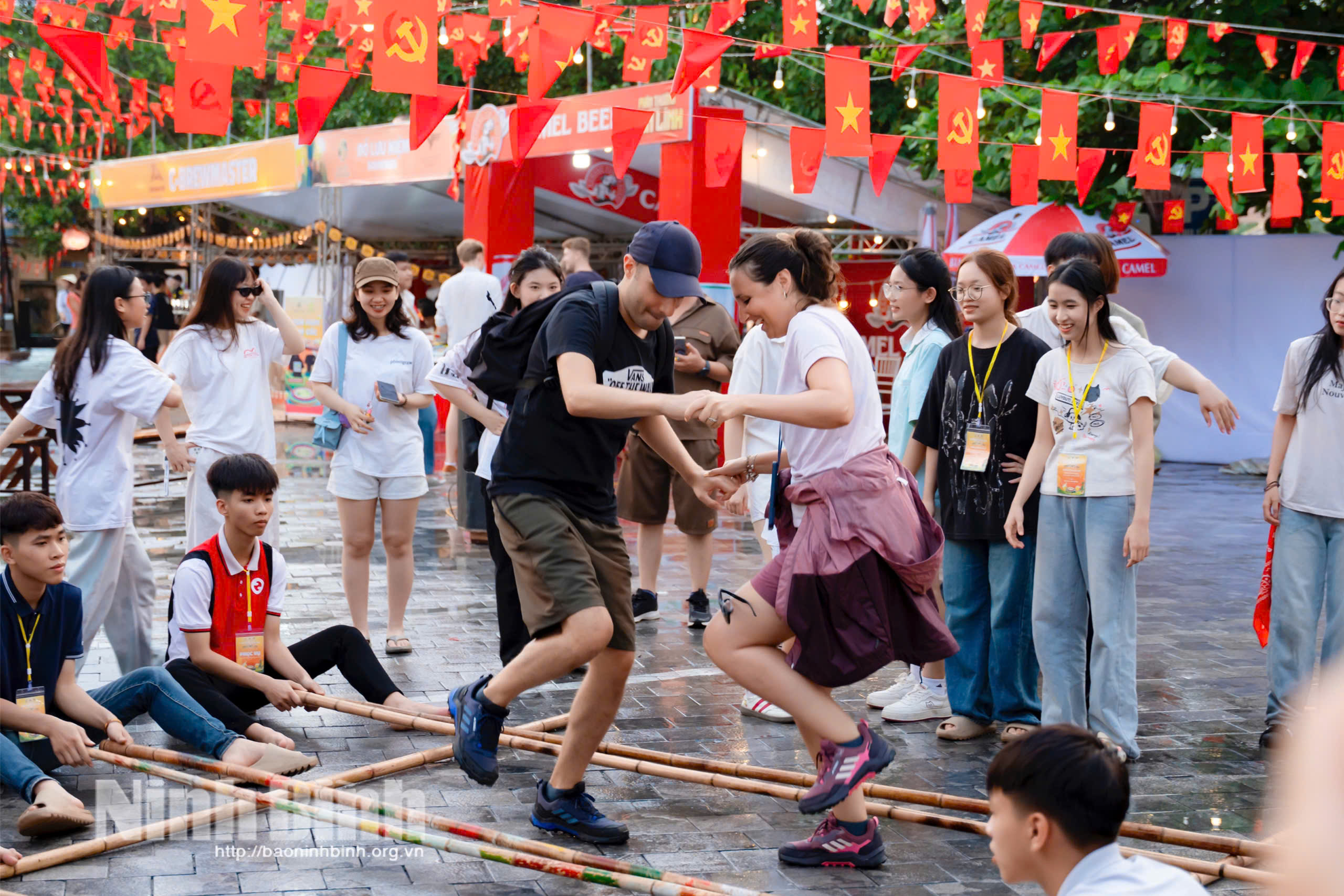 Foreign visitors experience bamboo dancing at Tam Coc tourist site.