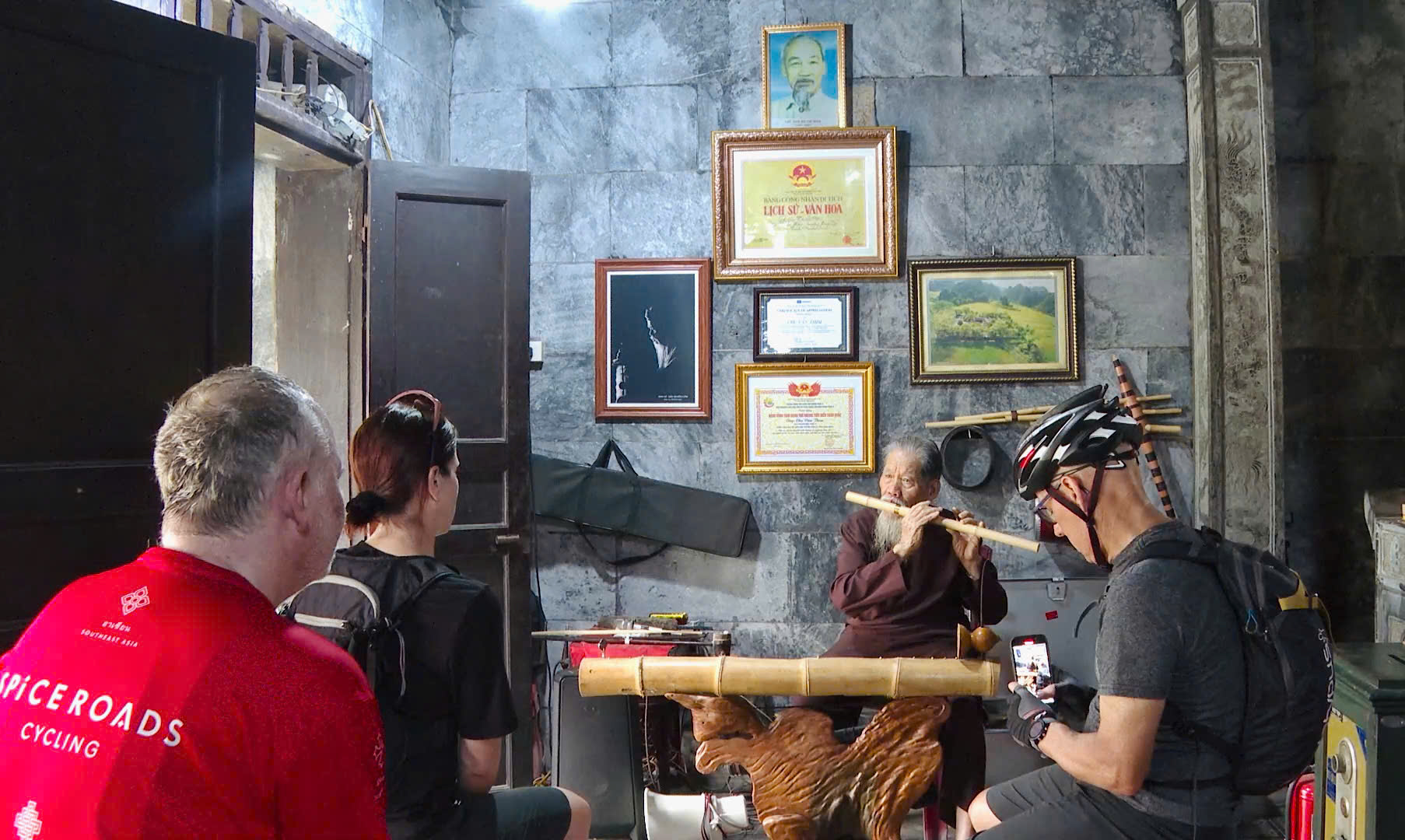 Du khách nước ngoài lắng nghe tiếng sáo trúc do cụ Chu Văn Thim biểu diễn.